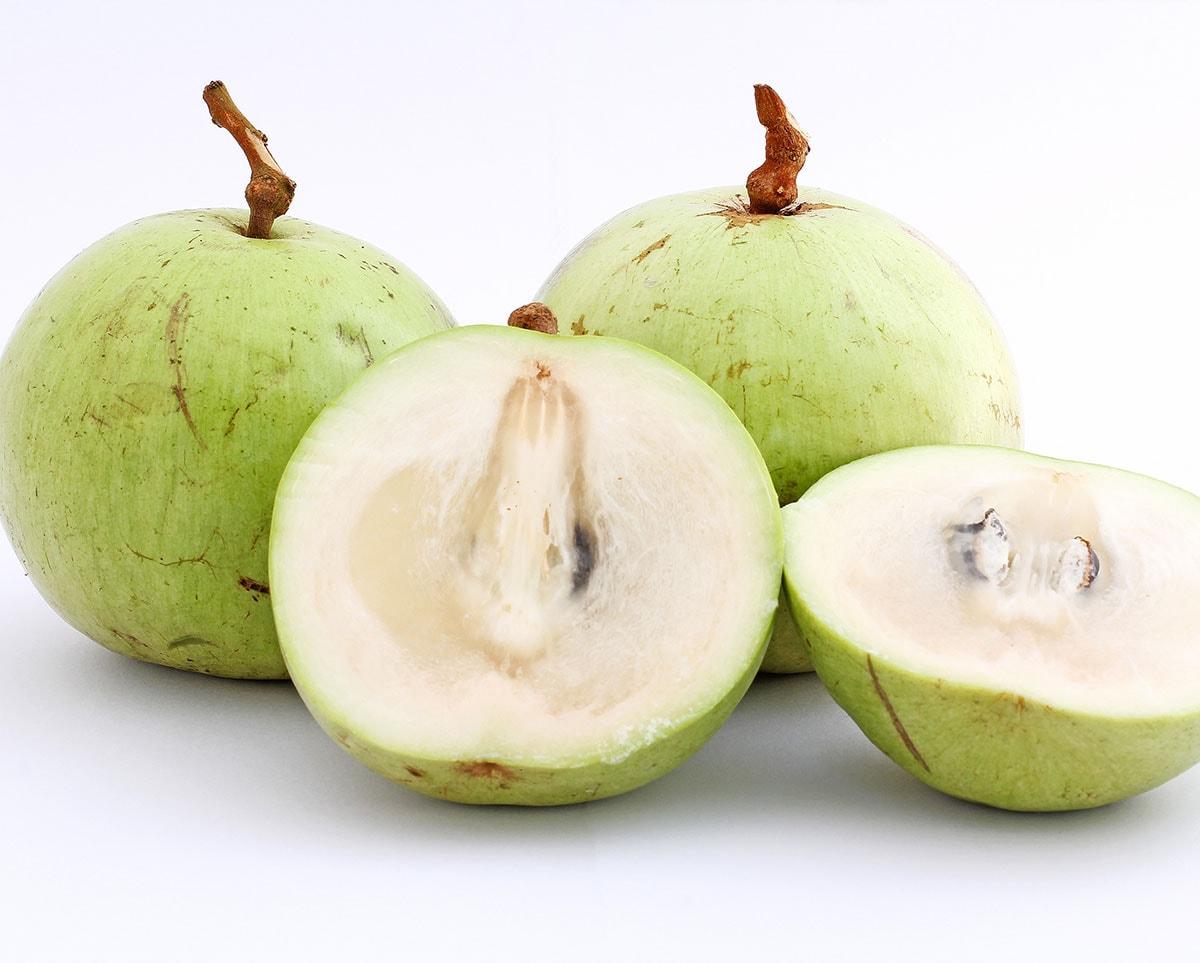 star apple with green skin and white flesh on a white background