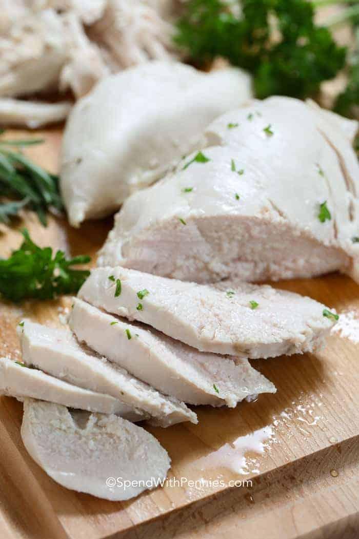 Slices of poached chicken on a wooden board